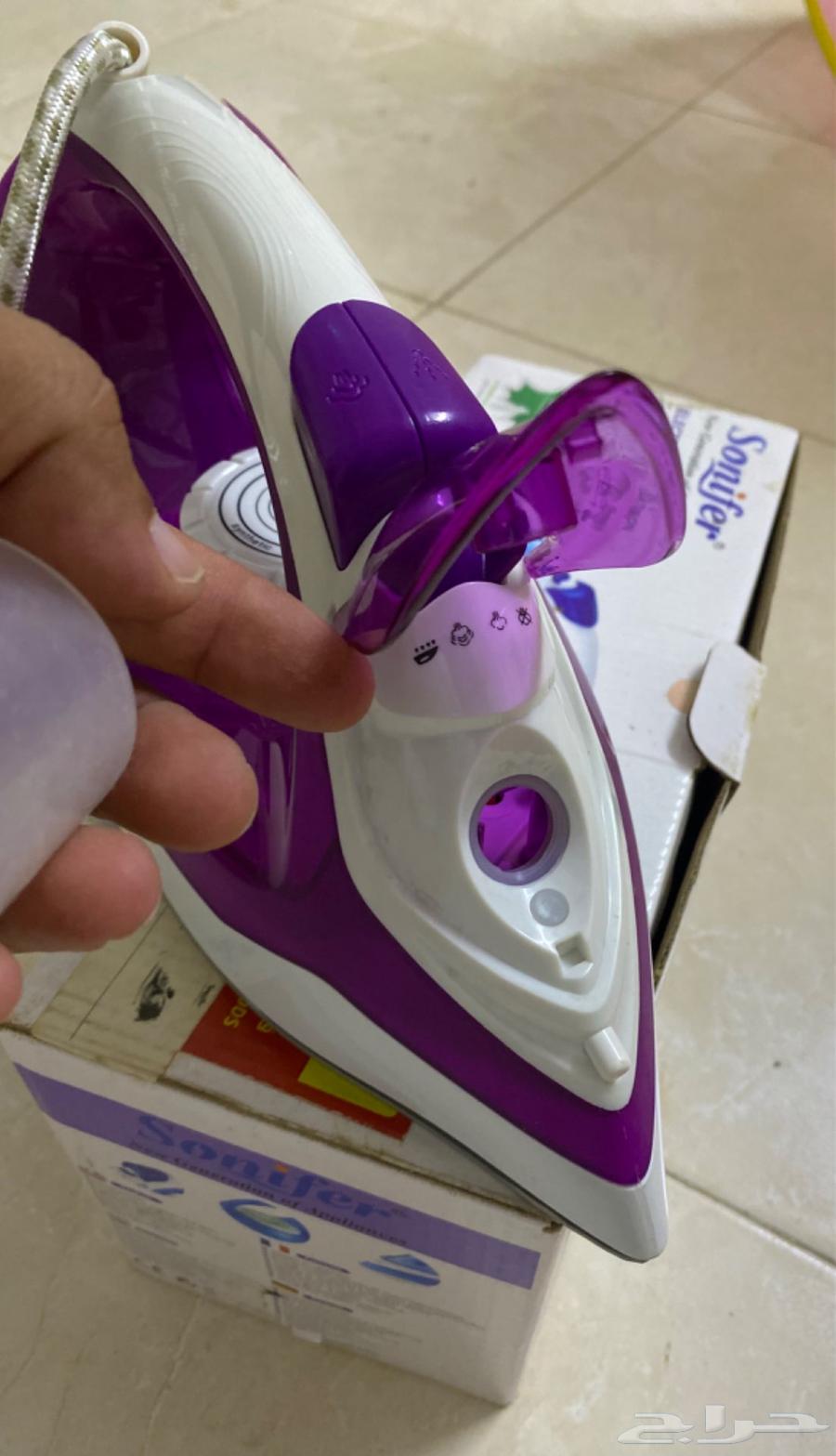 A new, unused handheld steam iron in its carton.63407539557378112